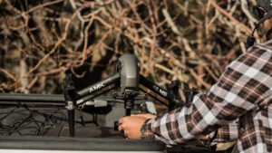 AMK Films crew swaps lenses on the DJI Inspire 2 drone during the Toyota Tacoma shoot in Wrightwood, California. The snowy forest backdrop highlights the precision and preparation required for capturing dynamic aerial shots.