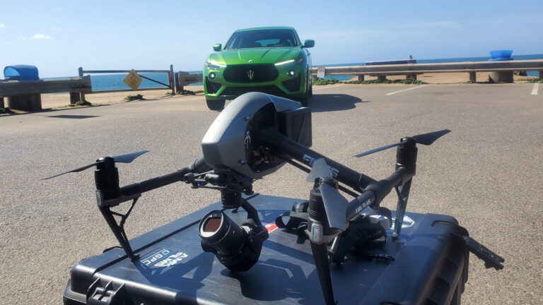 A striking behind-the-scenes shot from the Maserati Levante commercial in San Diego. The DJI Inspire 2 equipped with the X7 camera sits prominently in the foreground, perfectly framed against the edge of the ocean. In the background, the Maserati Levante is poised elegantly, ready to be captured in dynamic aerial footage.