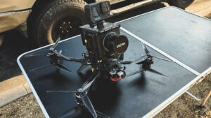 A behind-the-scenes shot of the AMK Films crew preparing a heavy-lift FPV drone for a dynamic shoot for Fila. Equipped with the RED Komodo camera, the drone is set to capture swooping shots through palm trees and close-up angles of a convertible. The setup reflects precision and creativity, ready to deliver cinematic visuals.