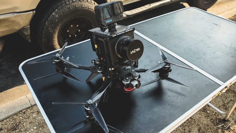 A behind-the-scenes shot of the AMK Films crew preparing a heavy-lift FPV drone for a dynamic shoot for Fila. Equipped with the RED Komodo camera, the drone is set to capture swooping shots through palm trees and close-up angles of a convertible. The setup reflects precision and creativity, ready to deliver cinematic visuals.